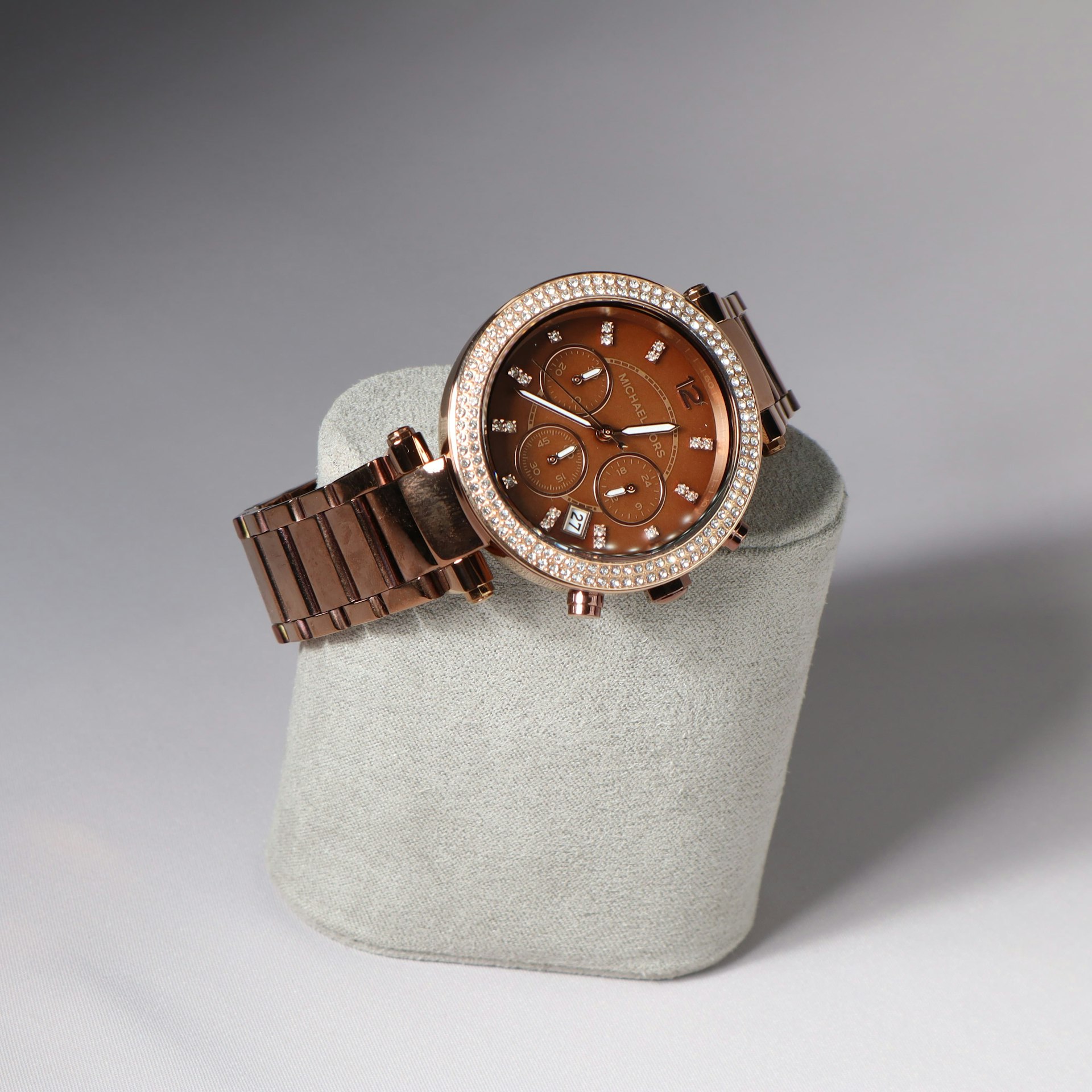 A stylish rose gold watch rests on a display.